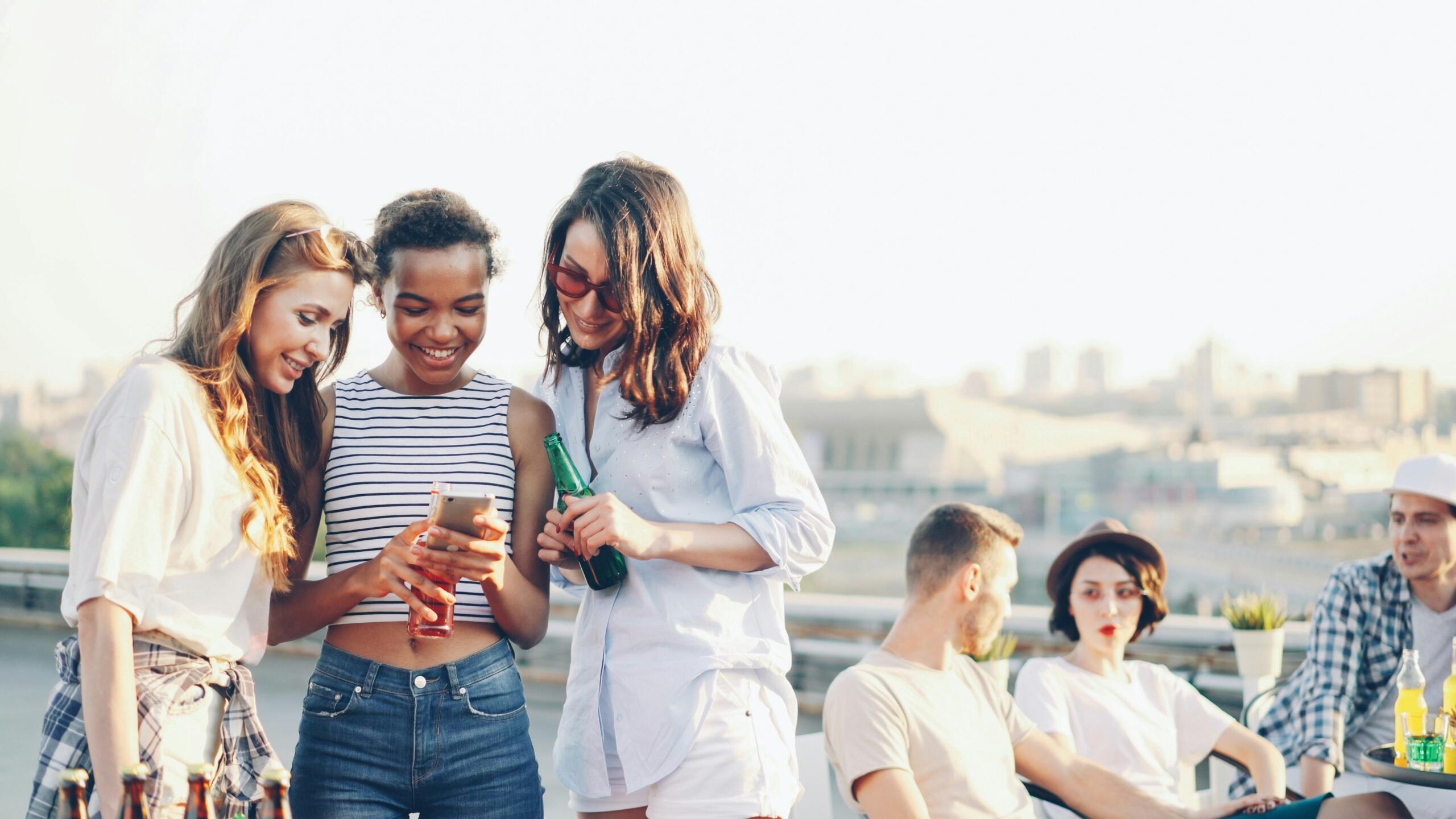 Noored sõbrad istuvad katuseterrassil ja vaatavad koos telefoni