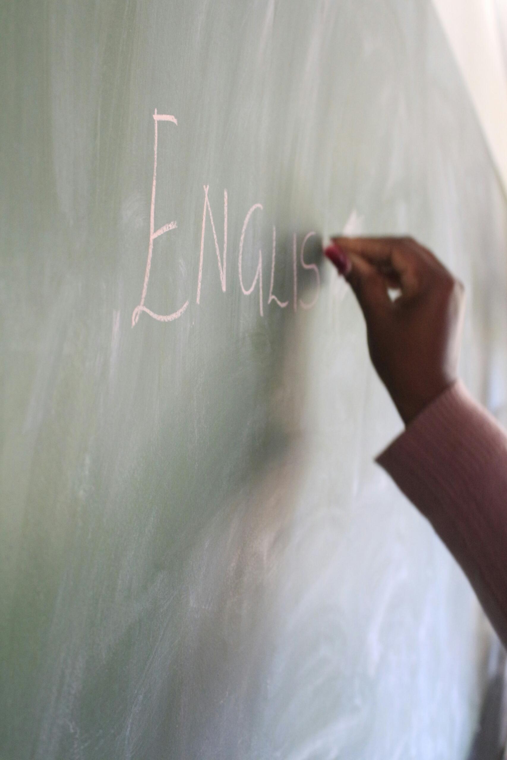 Käsi kirjutab tahvlile kriidiga sõna English