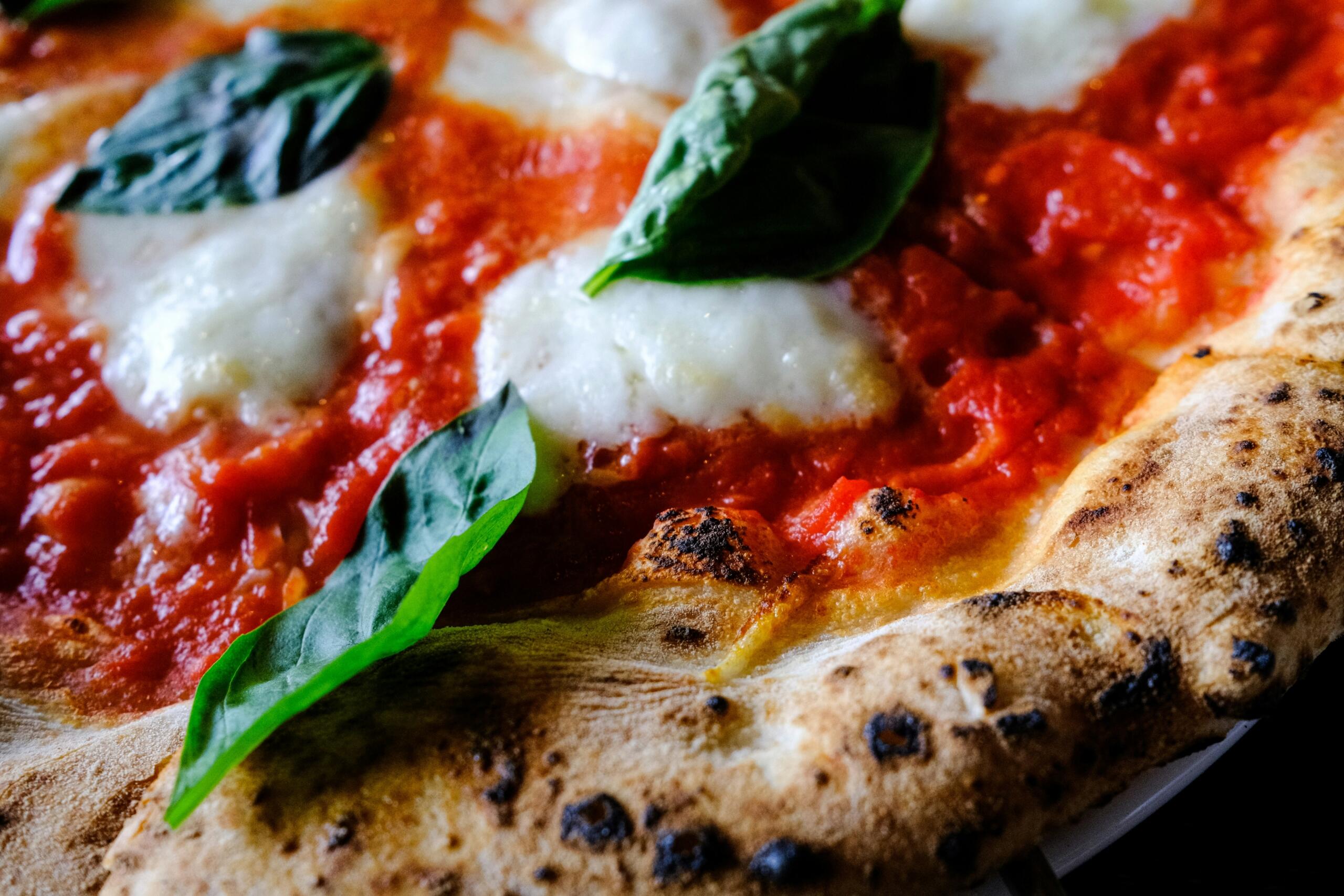 Lähivaade Margherita pitsale tomatikastme, mozzarella ja värske basiilikuga.
