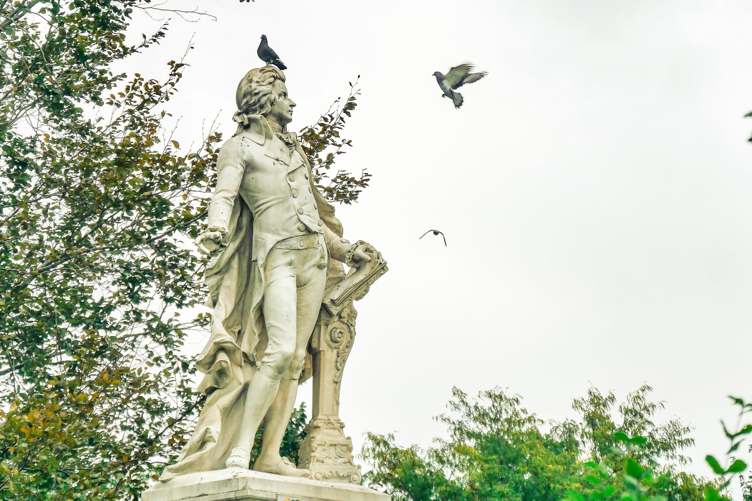 Helilooja monument pargis, taustal puud ja lendavad linnud.