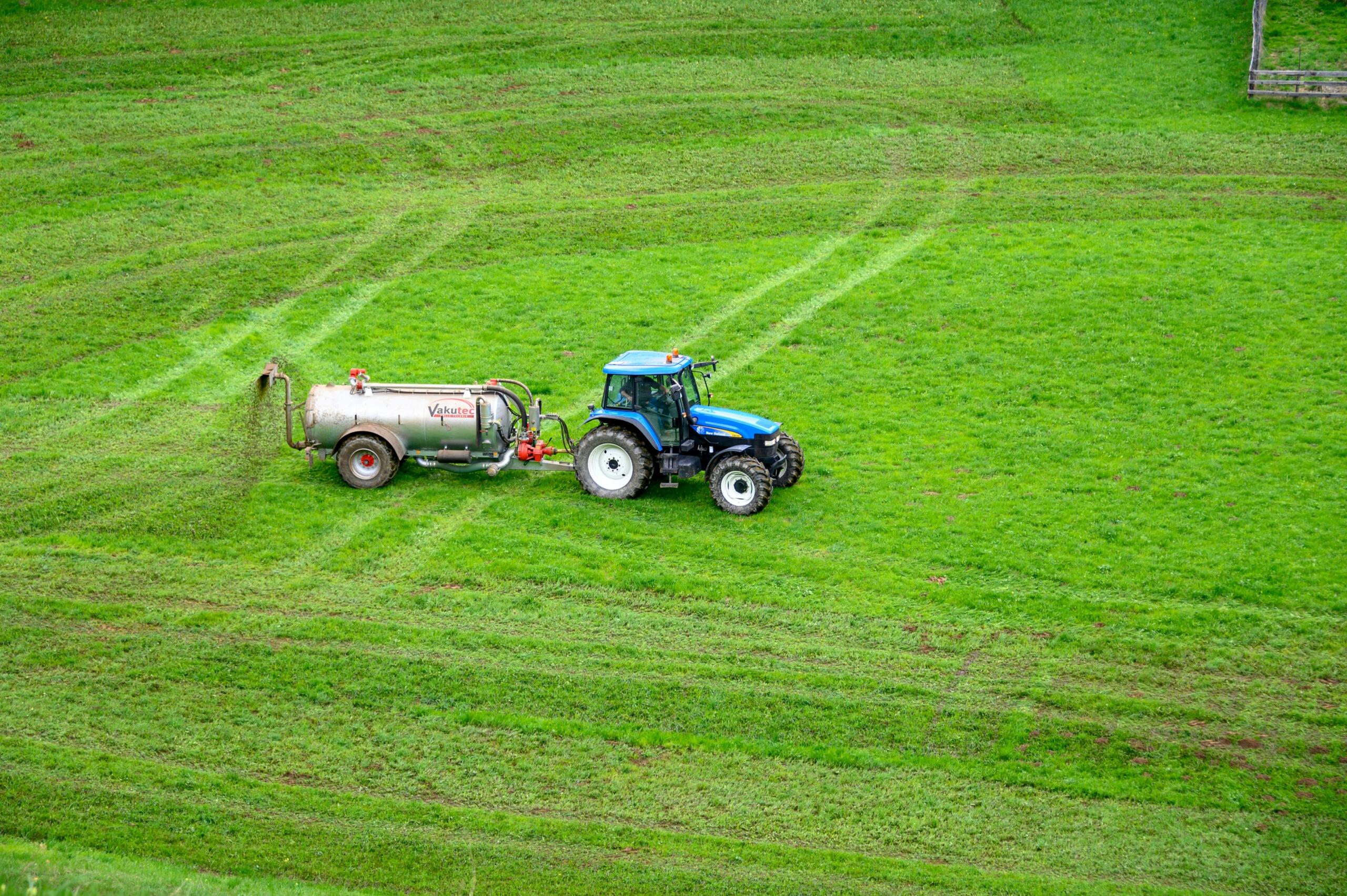 sinine traktor laotab rohumaale väetist