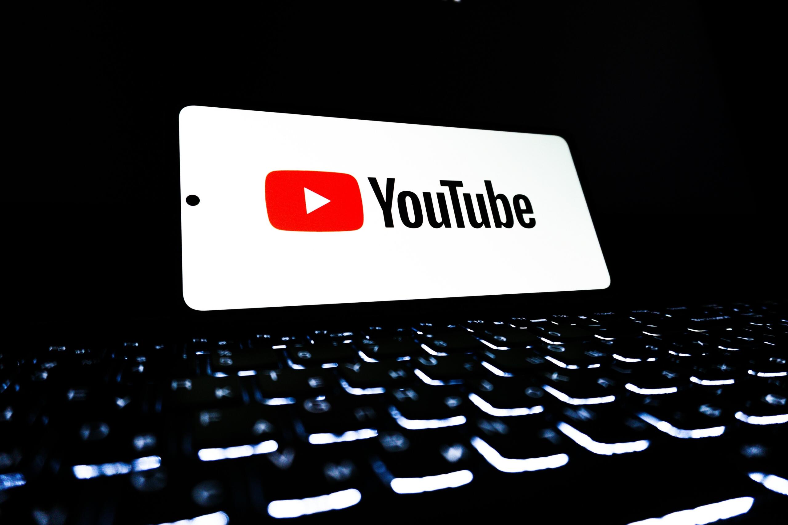 Tumeda taustaga fotol on valgustatud ekraan, millel on YouTube’i logo, ning esiplaanil paistab hämaralt arvutiklaviatuur