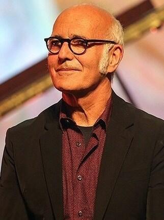 Ludovico Einaudi tumedas pintsakus ja punases särgis Teherani kontserdil, pilk suunatud küljele.