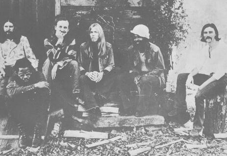 Kuus The Allman Brothers Bandi liiget istuvad õues trepiastmetel ja maja ees.