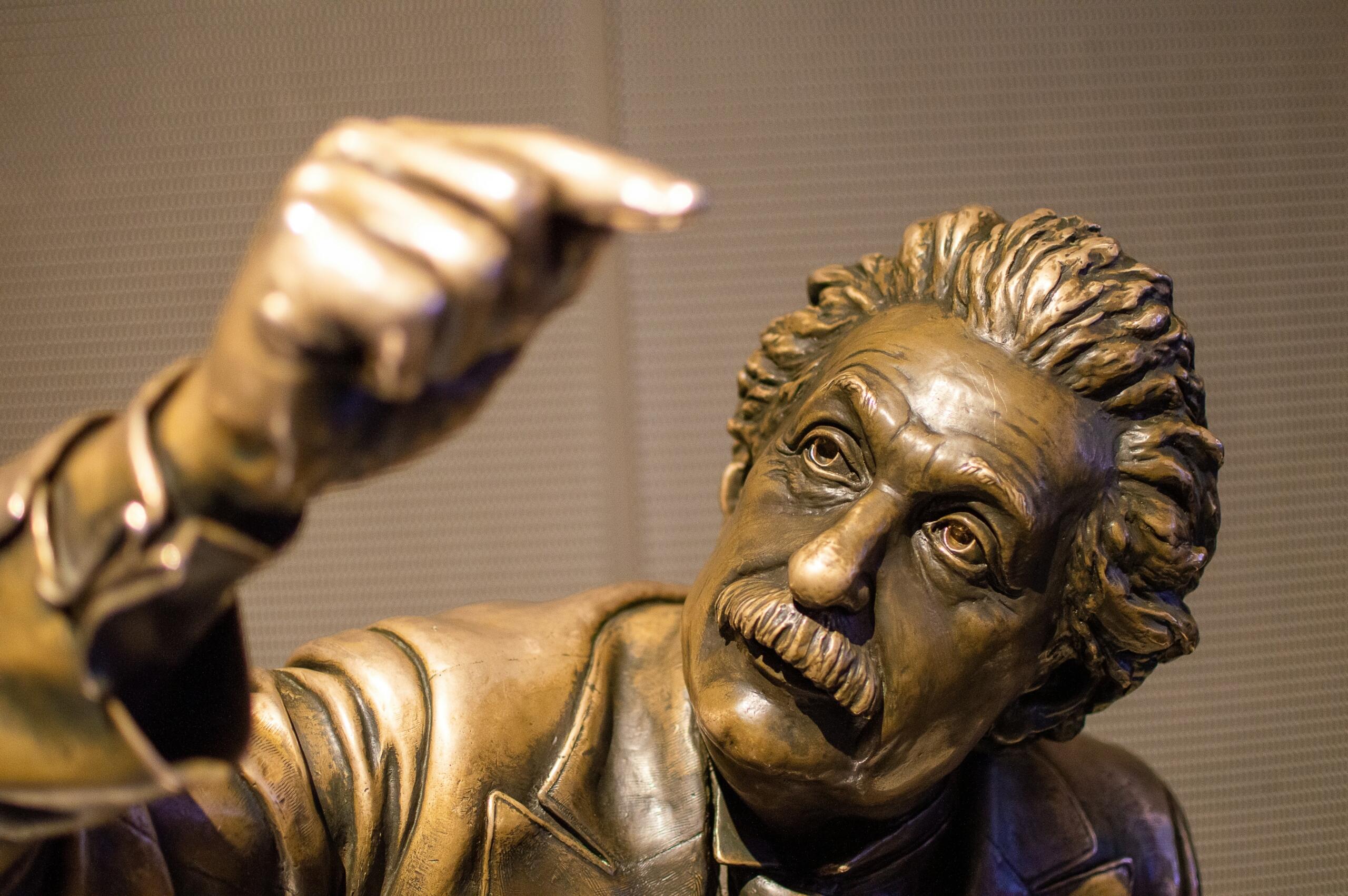 Pronksist Albert Einsteini skulptuur, millel on kujutatud sasitud juuste ja vuntsidega teadlast, kes vaatab ülespoole ning hoiab üht kätt tõstetuna.