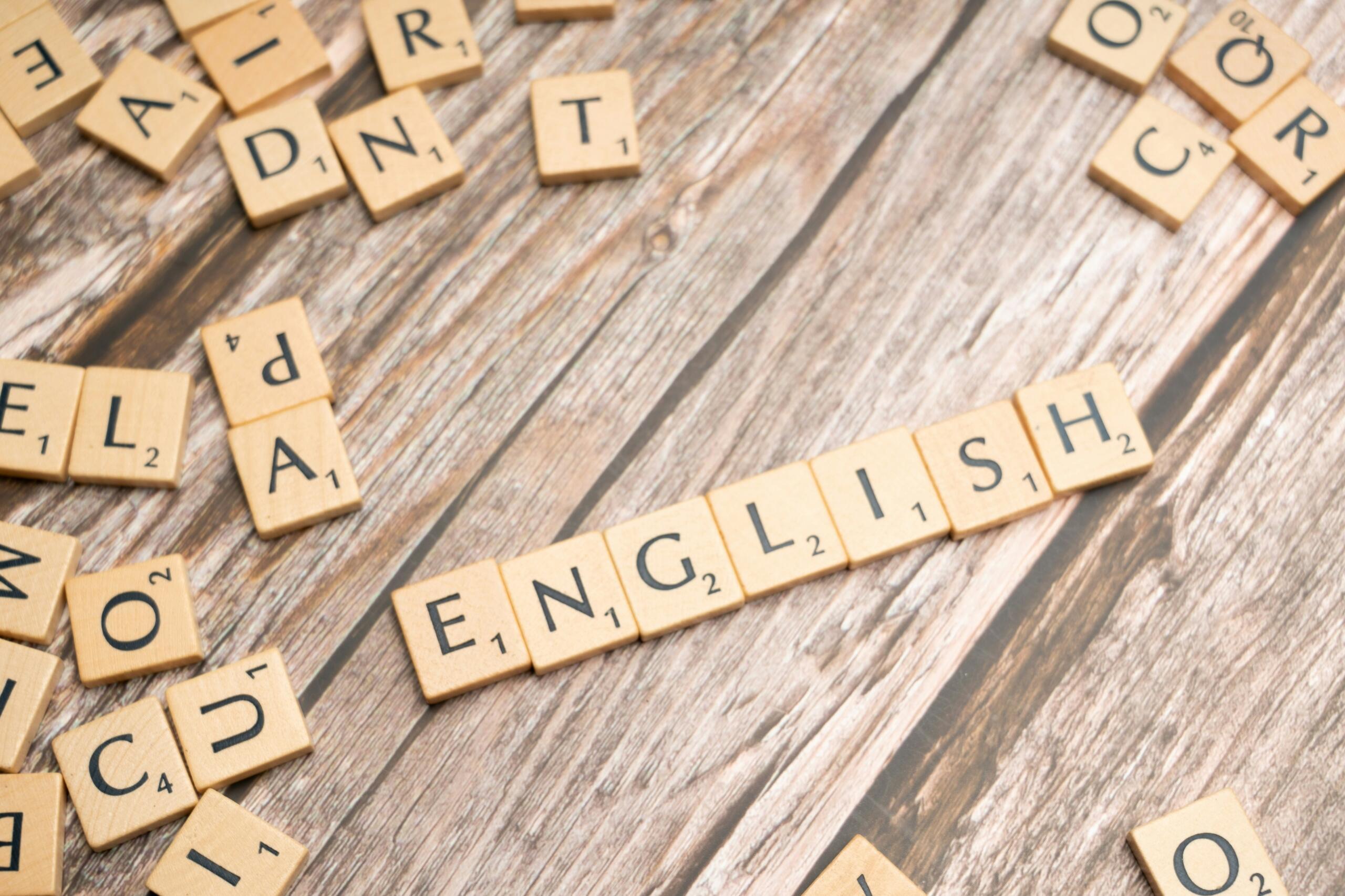 Fichas de Scrabble esparcidas sobre una superficie de madera con la palabra «ENGLISH» formada en el centro.