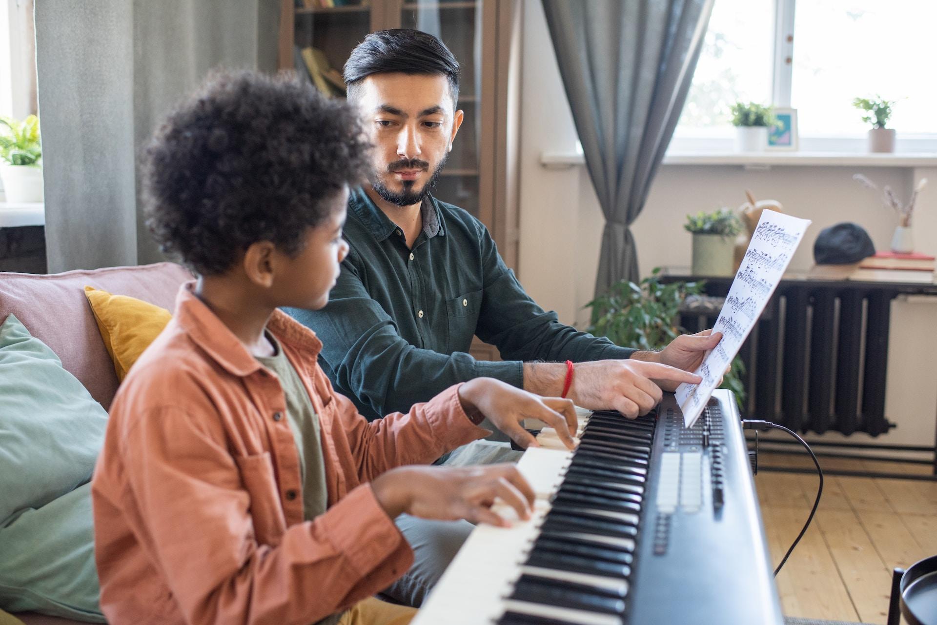 Profesor enseñando piano a un niño.