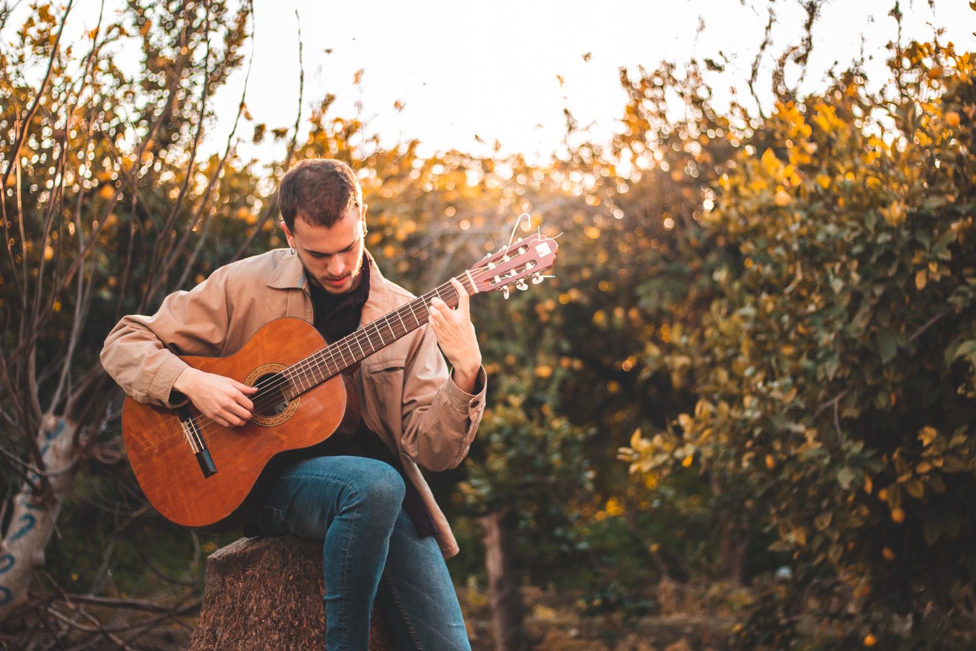 hombre tocando guitarra rodeado de flores