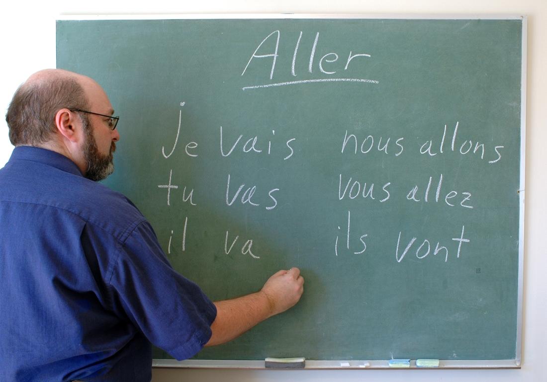 Profesor dando clases de francés en la pizarra.