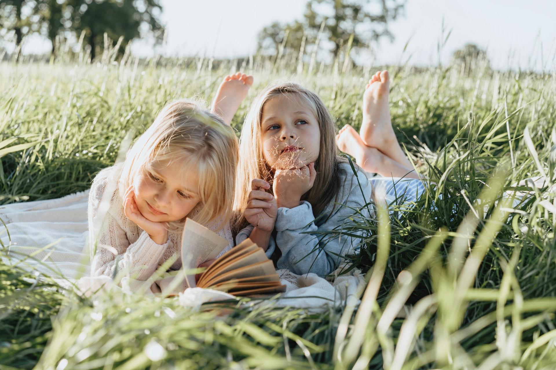 Niñas leyendo un libro en la arena.