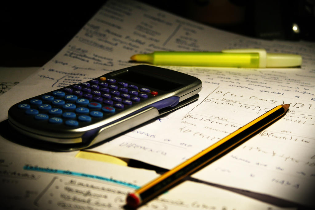 Hojas con problemas matemáticos junto con calculadora y lápices