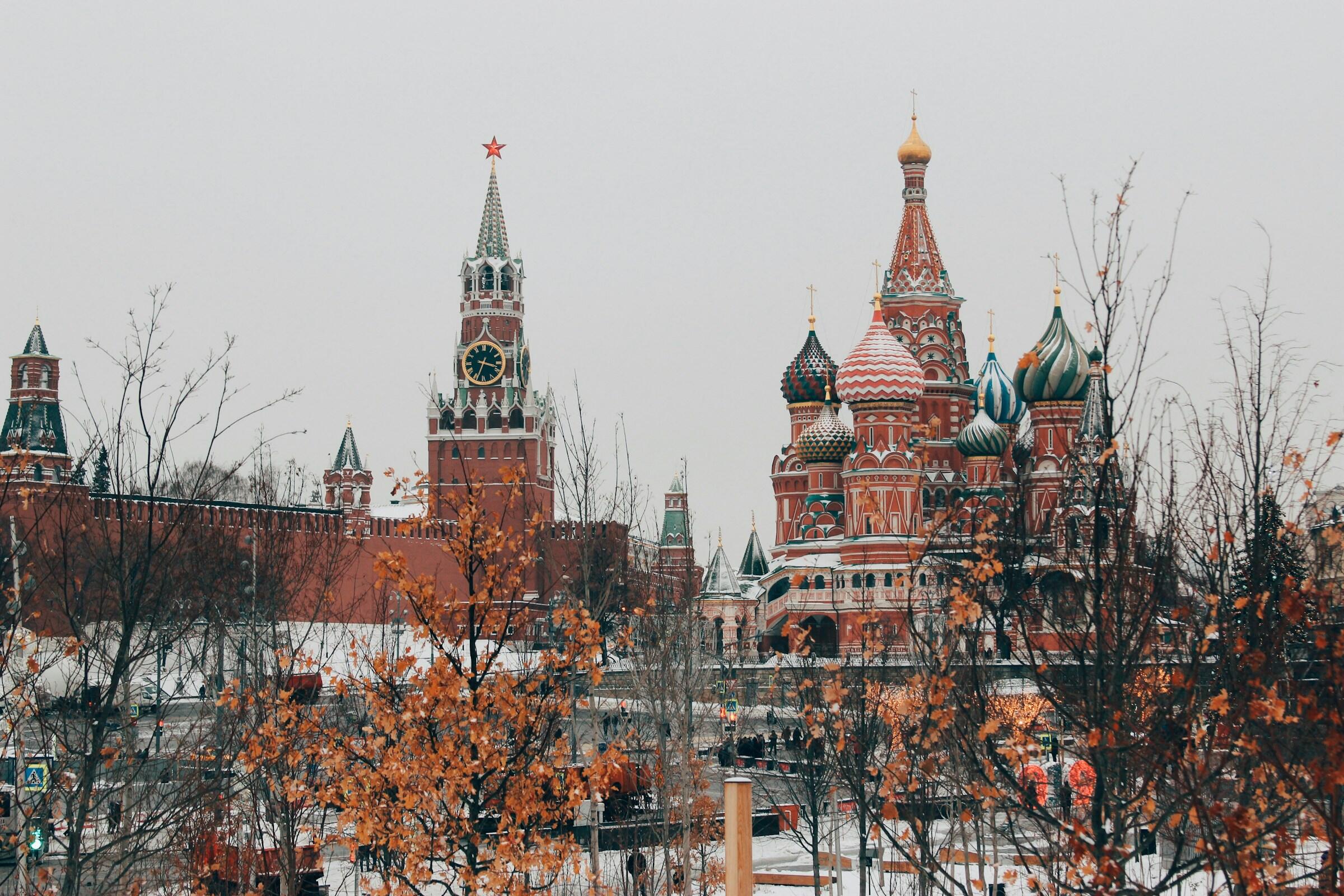 Kremlin y catedral de San Basilio en Moscú con árboles invernales en primer plano.