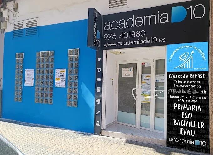 Exterior de Academia D10, con una fachada azul y blanca y un prominente letrero negro con la información de contacto. Hay carteles que anuncian clases particulares.