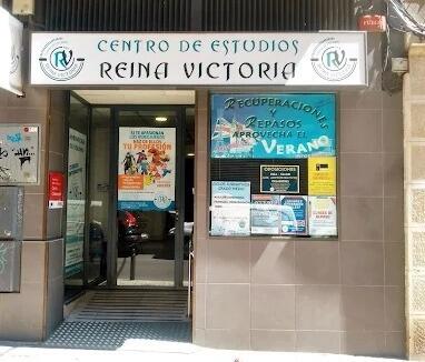 Vista exterior del «Centro de Estudios Reina Victoria», con varios carteles educativos en la entrada acristalada. Entorno luminoso e informativo.