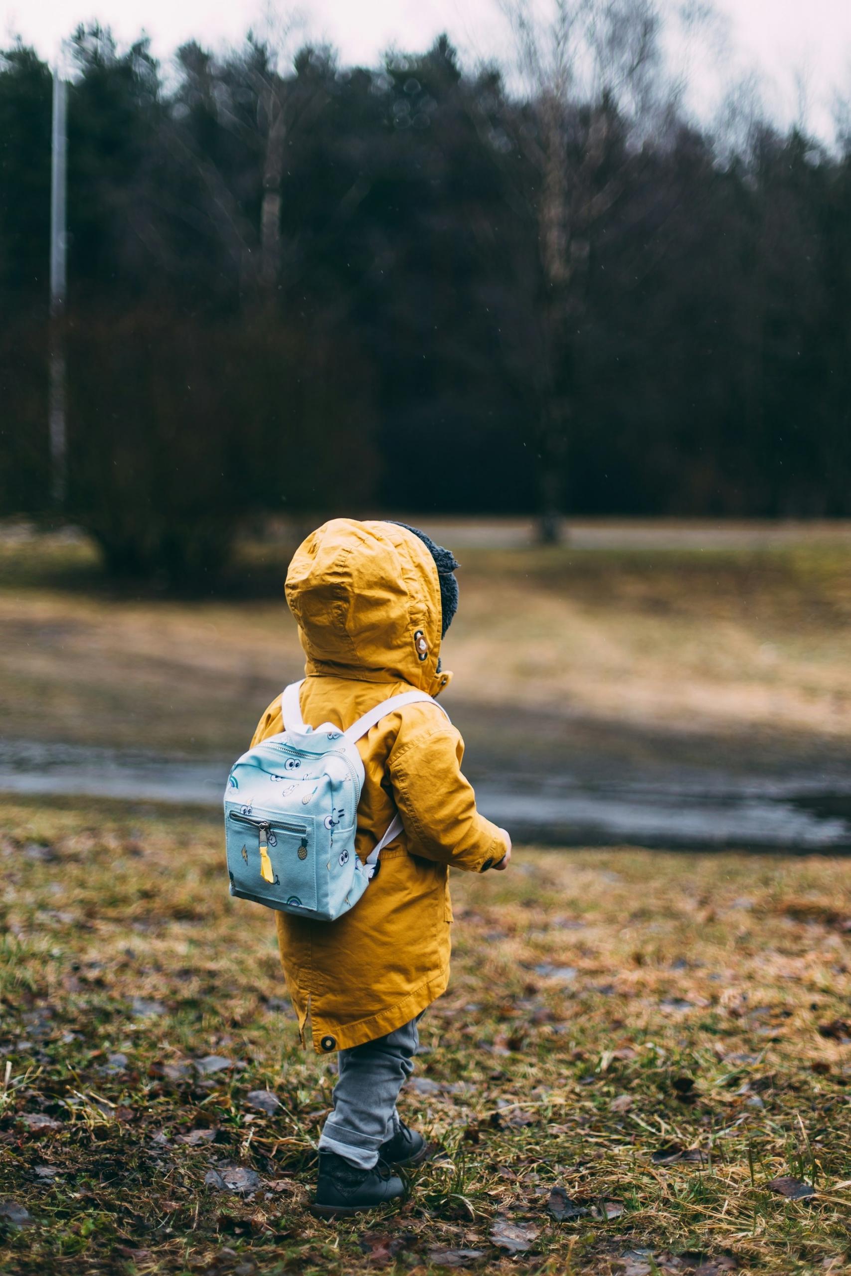 Niño paseando con abrigo y mochila.