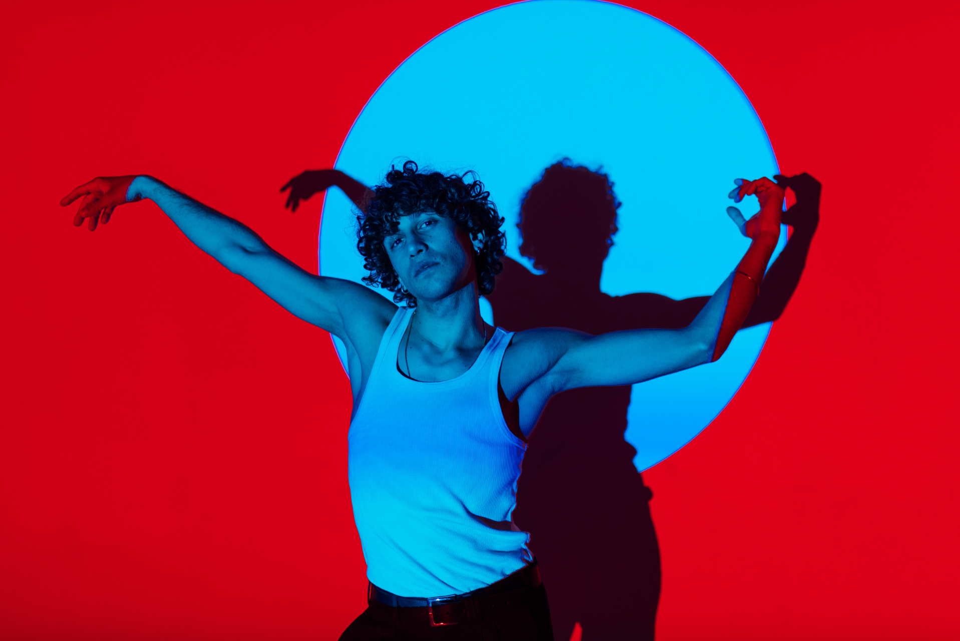 hombre bailando sobre fondo rojo con sus brazos levantados