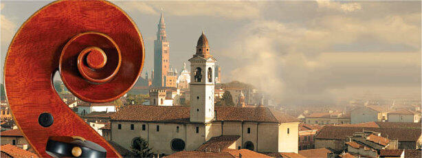 En primer plano se ve el remate de un violín, con vistas a una ciudad italiana con edificios históricos. Al fondo, se alza una alta torre del reloj contra un cielo nublado.
