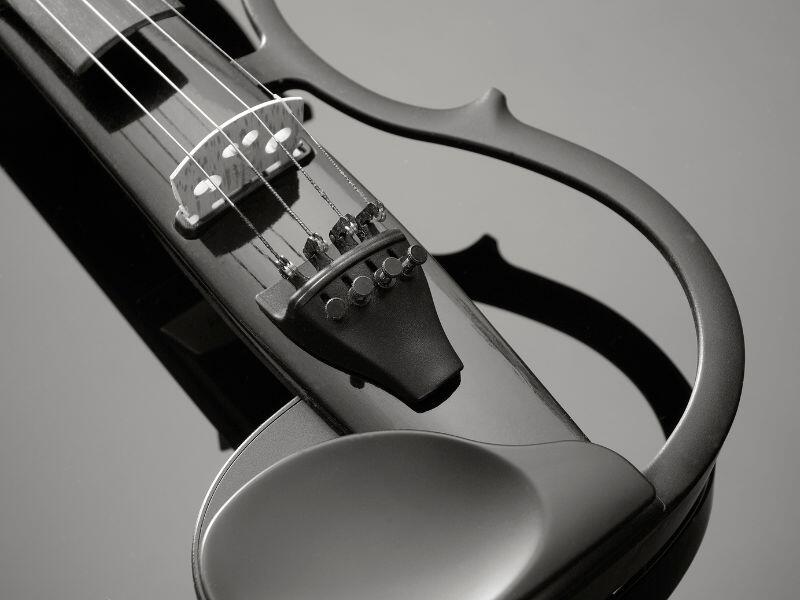 Primer plano de un elegante violín eléctrico negro sobre una superficie reflectante. Las cuerdas y el diapasón están enfocados, resaltando su diseño moderno y elegante.