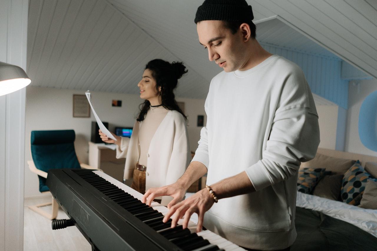 Chico tocando el piano y chica cantando.