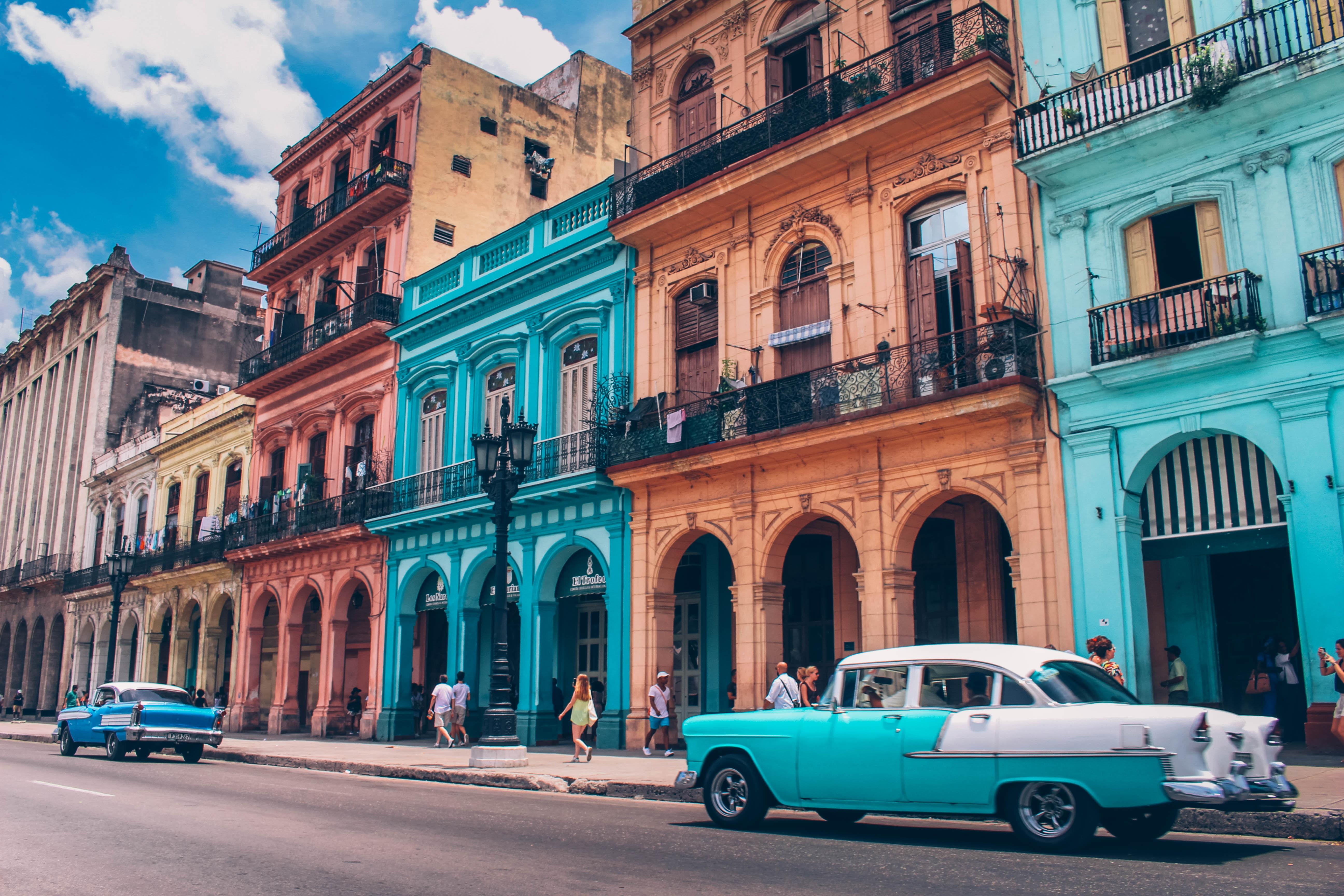 Casas viejas de color azul claro y crema, con berlinas, propias de la Habana