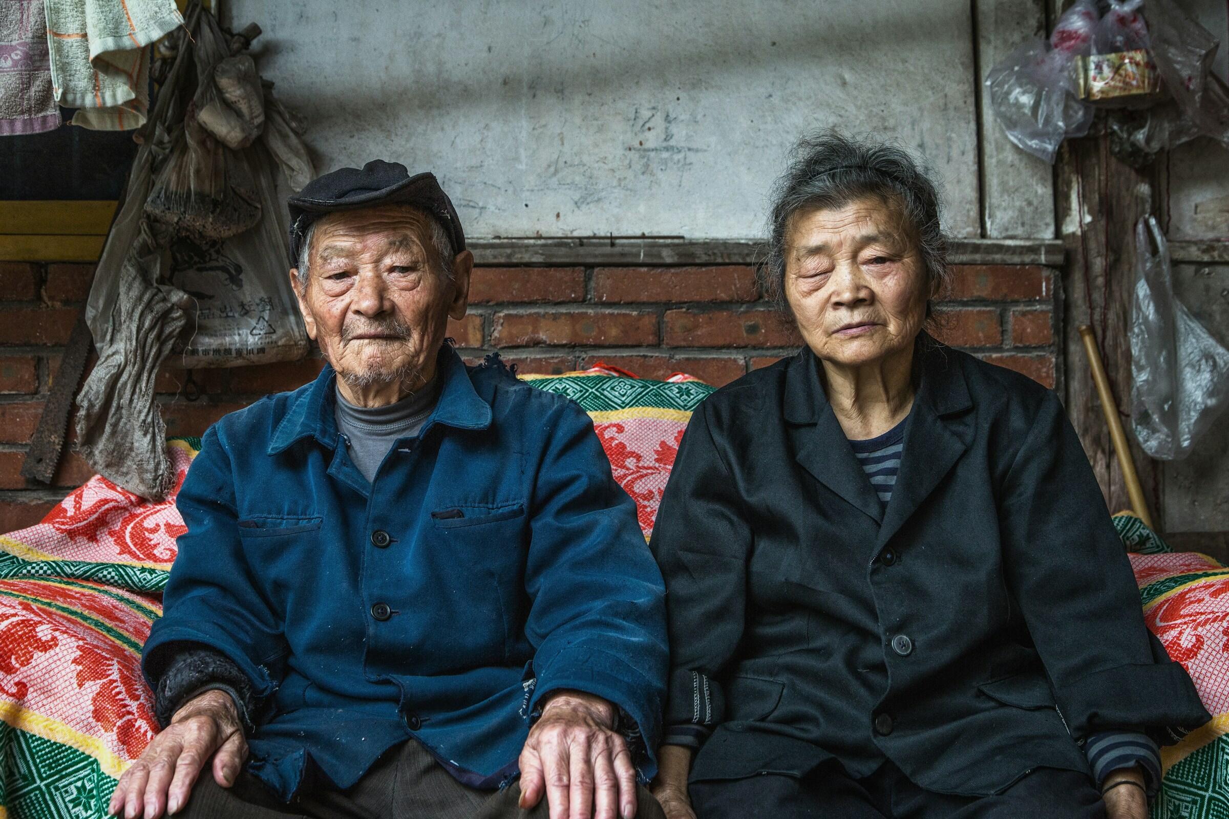 Un primer plano de un anciano y una anciana  chinos con gesto serio con rasgos faciales marcados por la edad.