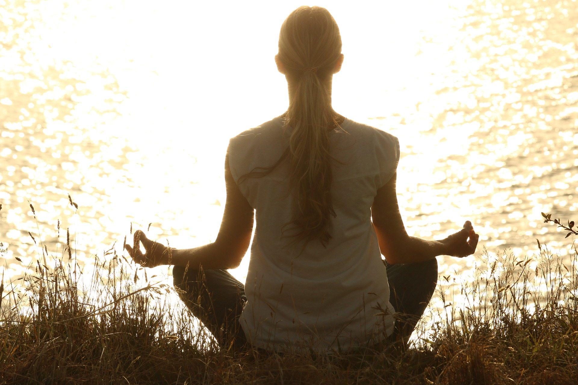 Mujer meditando a la orilla del lago