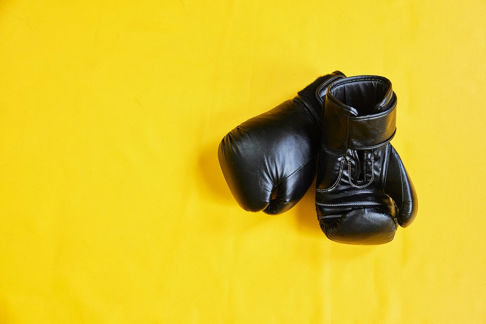 un par de guantes negros sobre caja amarilla
