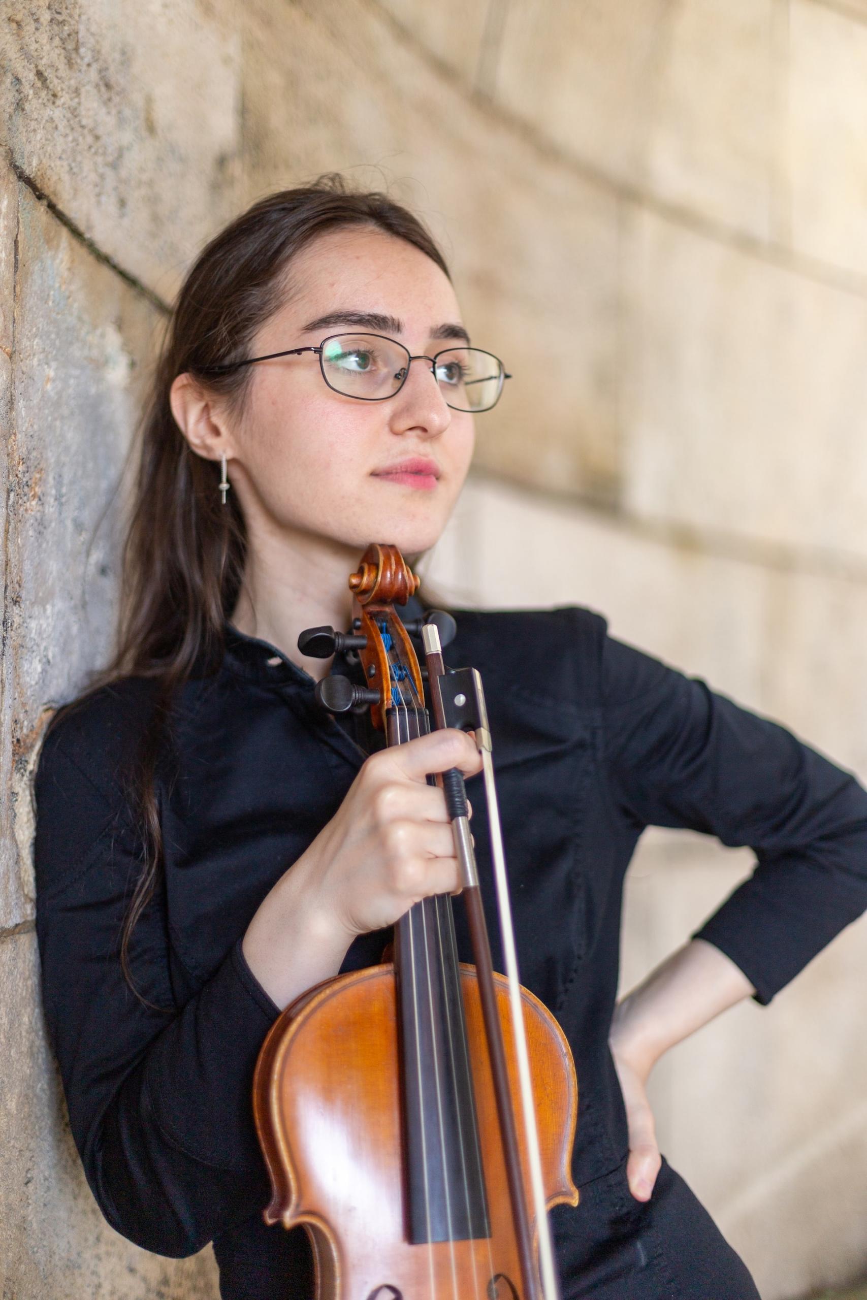 Chica sujetando un violín.