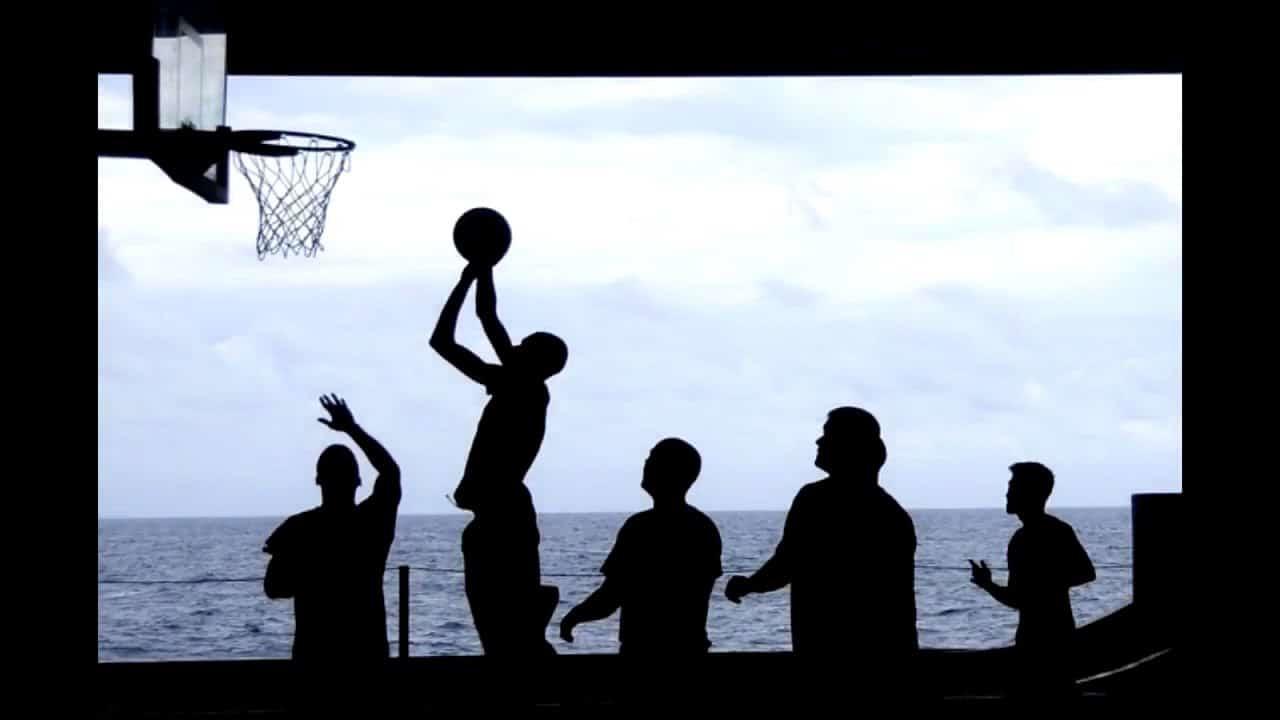 Grupo de amigos jugando basketball frente al mar