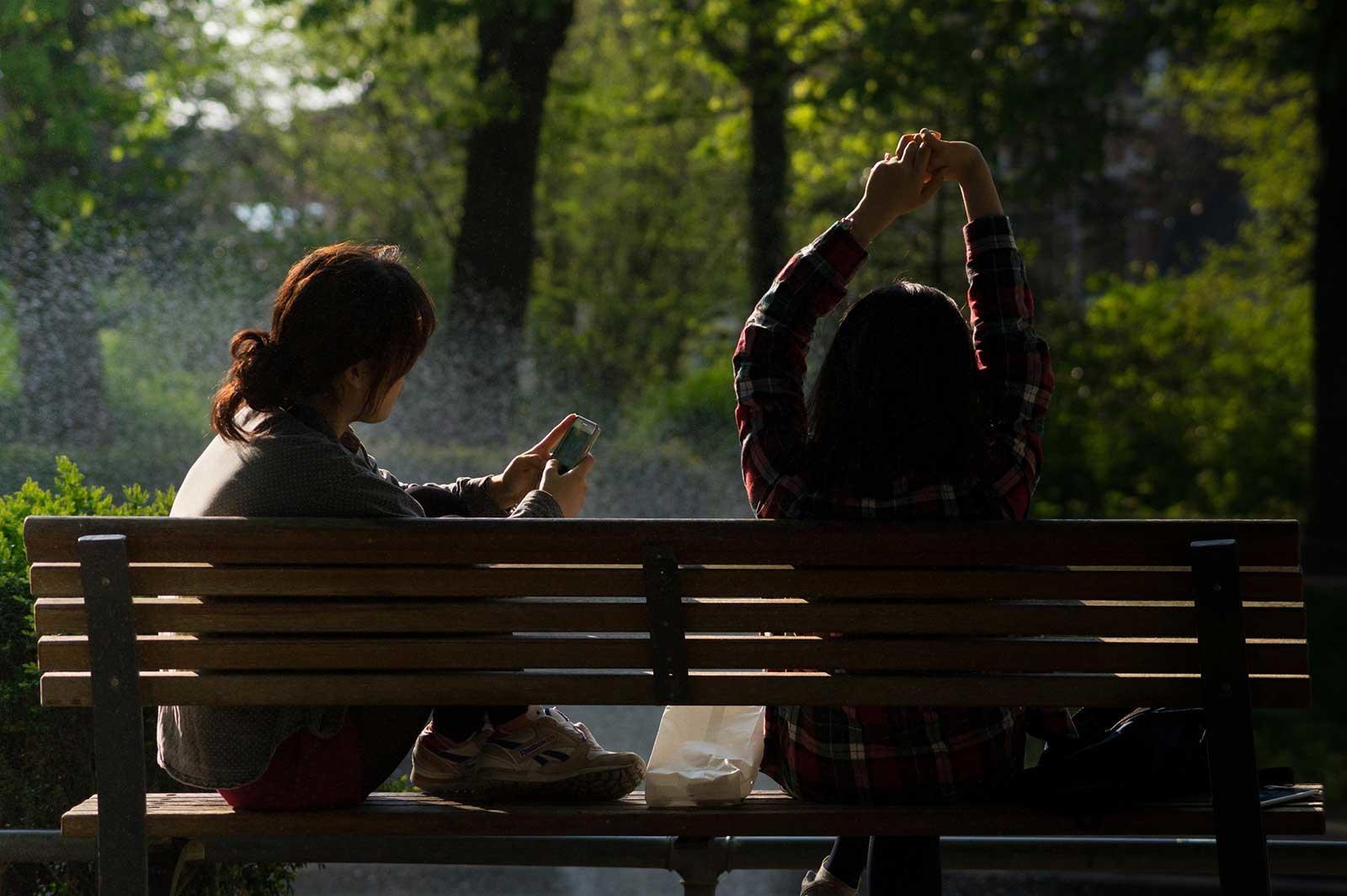 Dos chicas sentadas en la banca de un parque