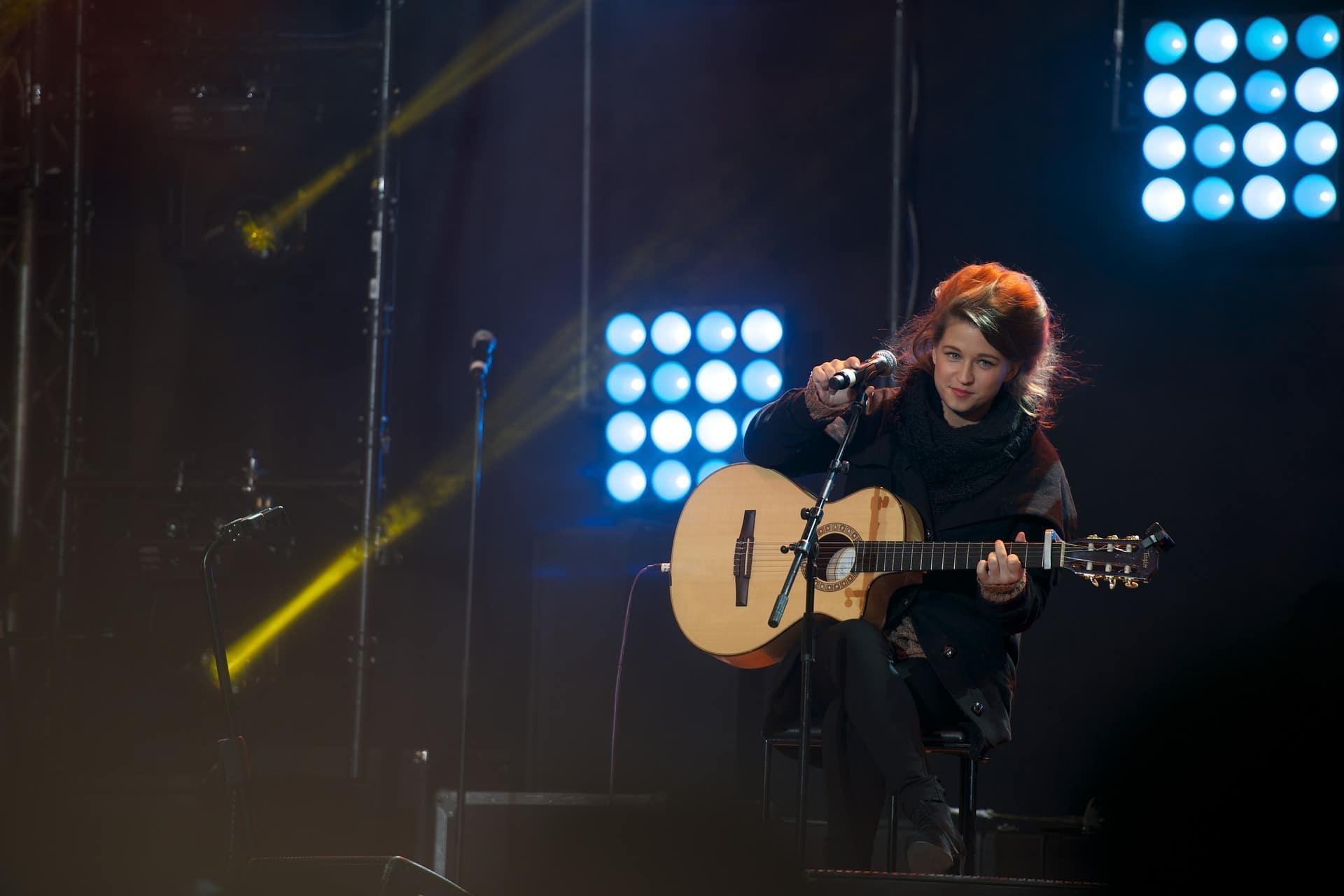 Mujer en escenario tocando guitarra