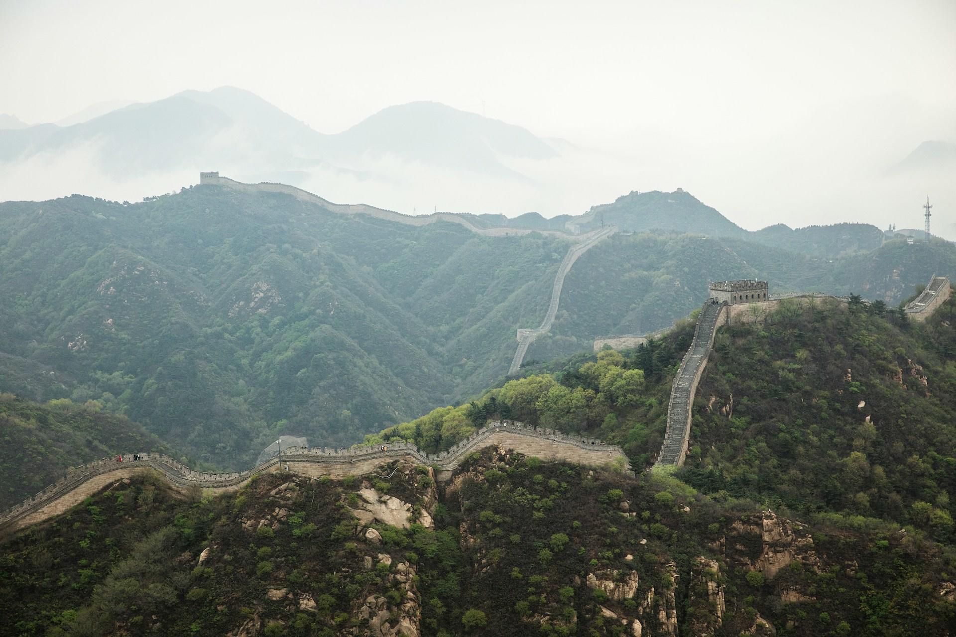 La Gran Muralla China serpentea a través de un brumoso paisaje montañoso.