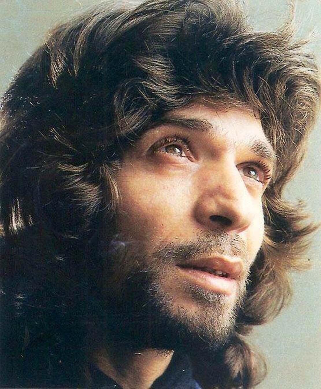 Camarón de la Isla con cabello largo y ondulado mira hacia arriba con una expresión pensativa y serena. La imagen es un primer plano que captura la suave luz sobre su rostro.