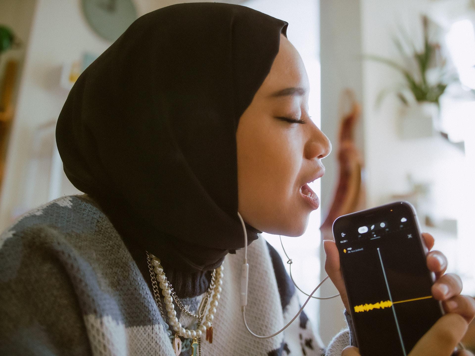 Mujer grabando su voz en el móvil.