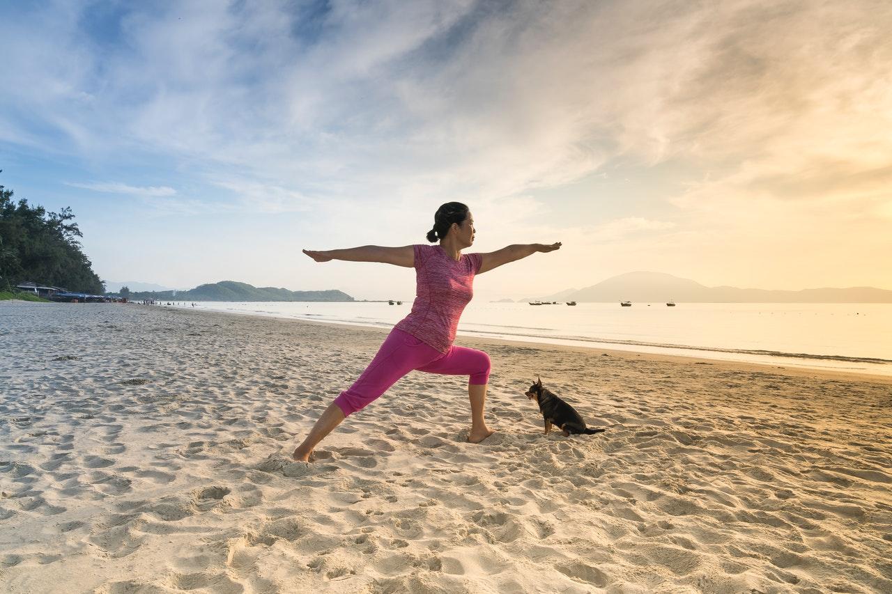 Mujer haciendo yoga en la playa.