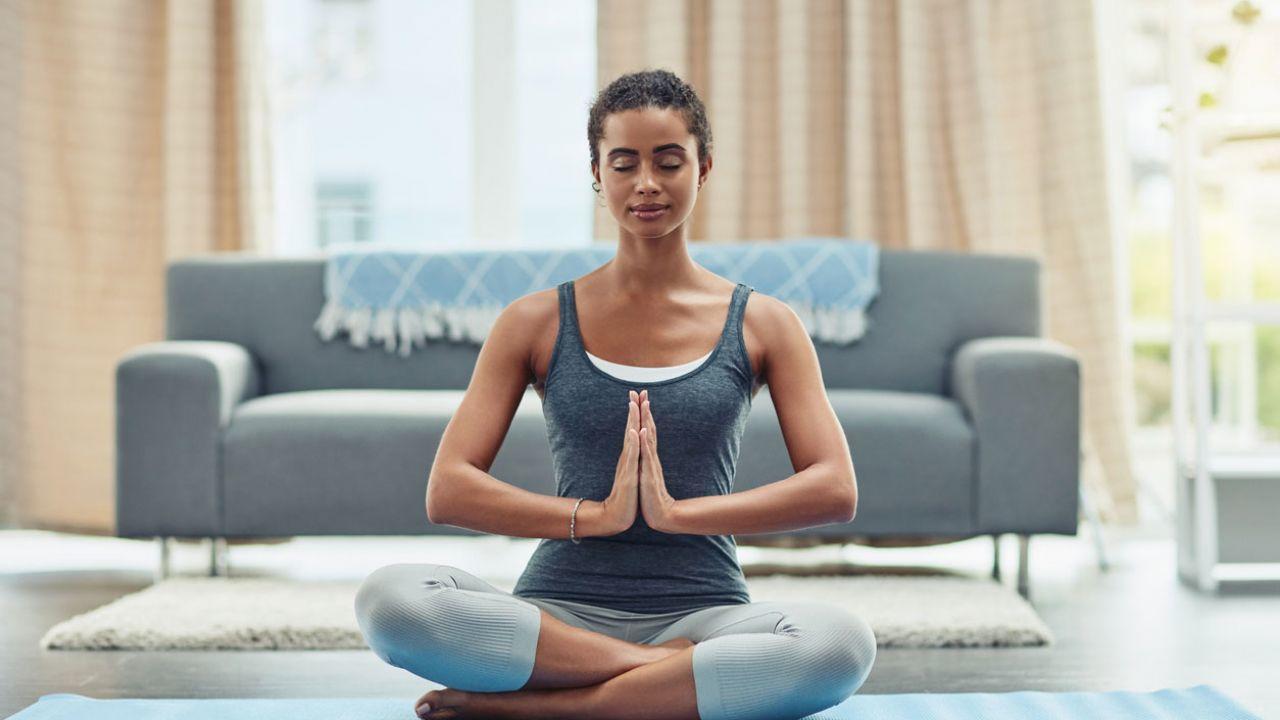 Chica practicando meditación en la sala de la casa