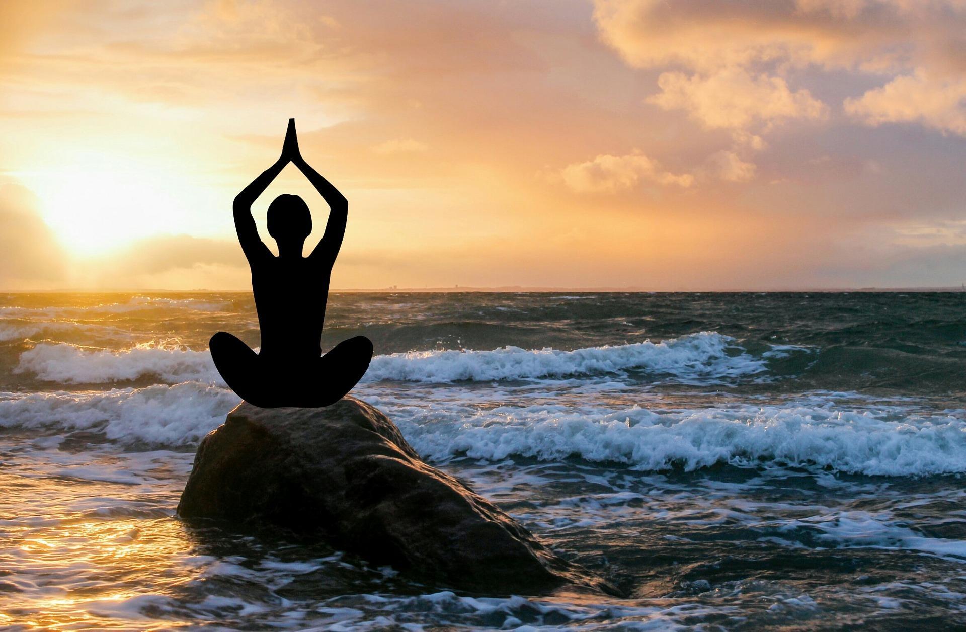 Silueta meditando en el relajante mar de ocaso