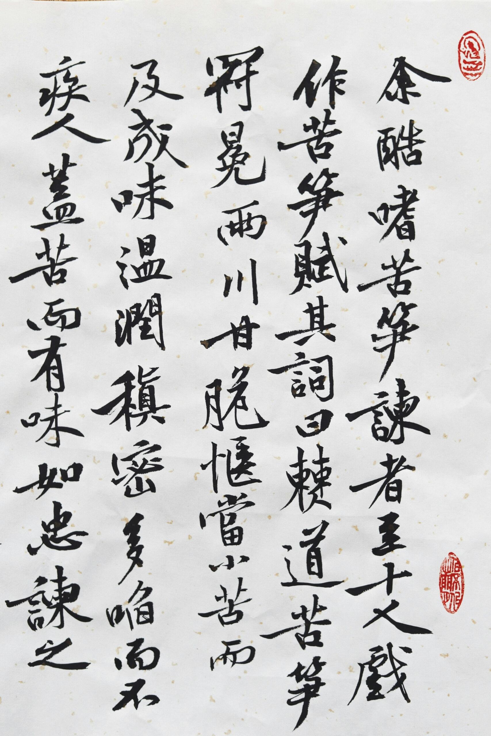 Primer plano de caligrafía tradicional china sobre papel texturizado, con caracteres intrincados y un sello rojo.