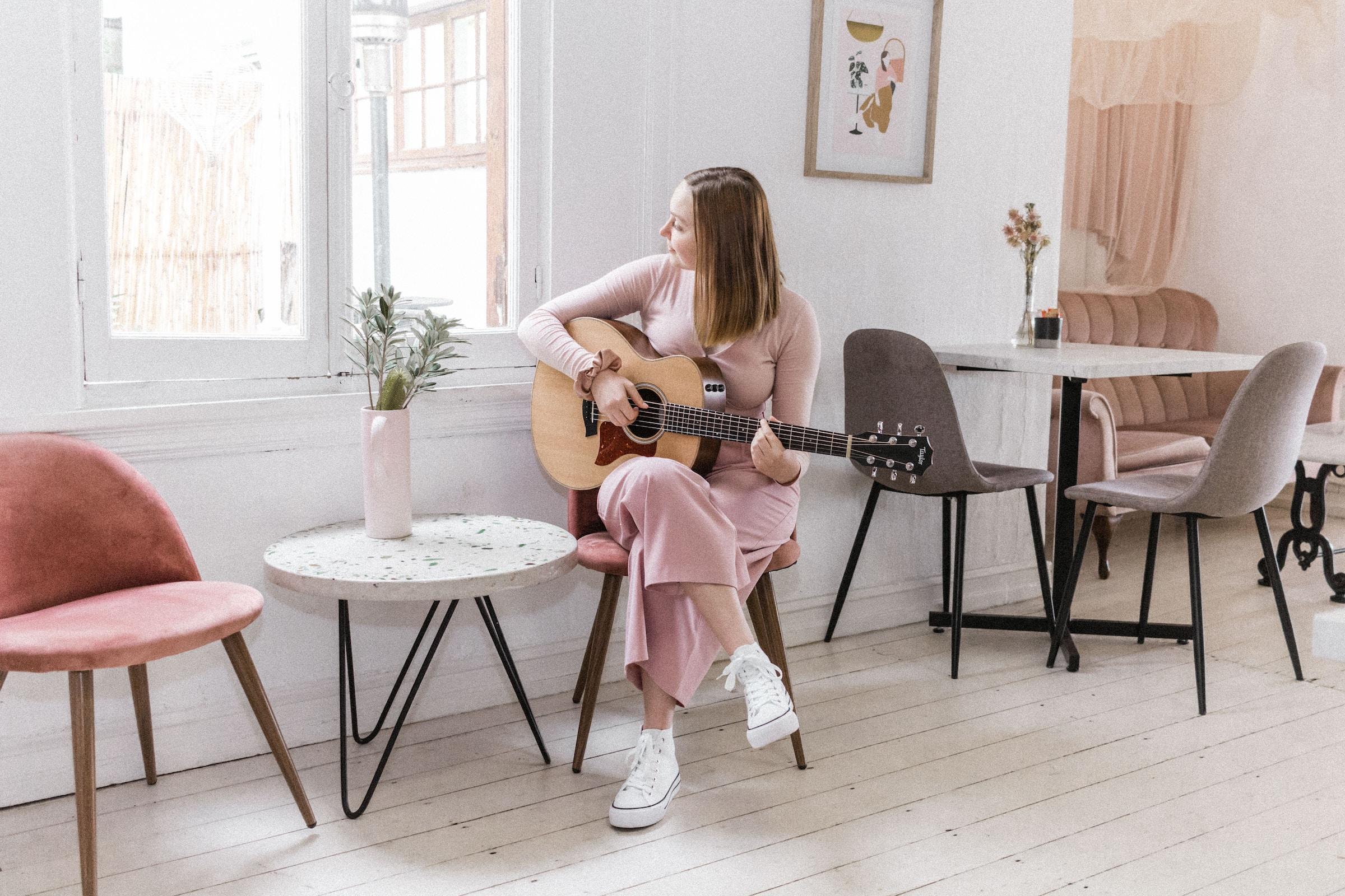 Chica tocando la guitarra en casa.