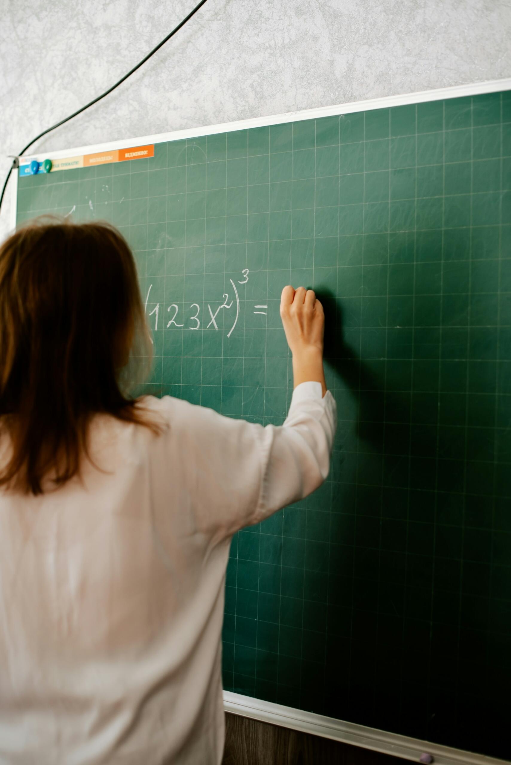 Persona escribiendo una ecuación matemática en una pizarra.