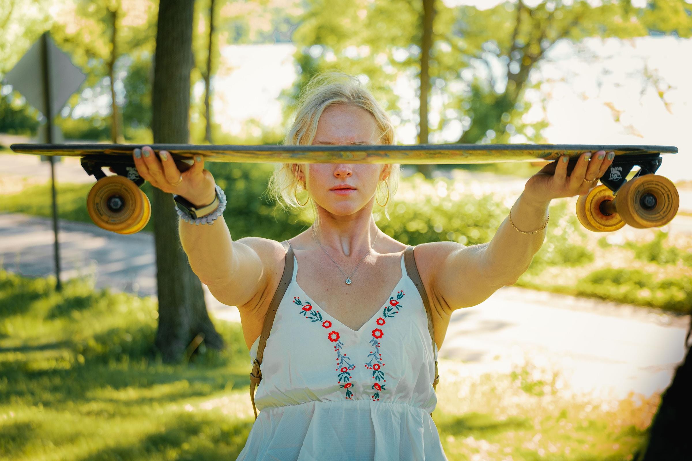 Chica sujetando un monopatín.