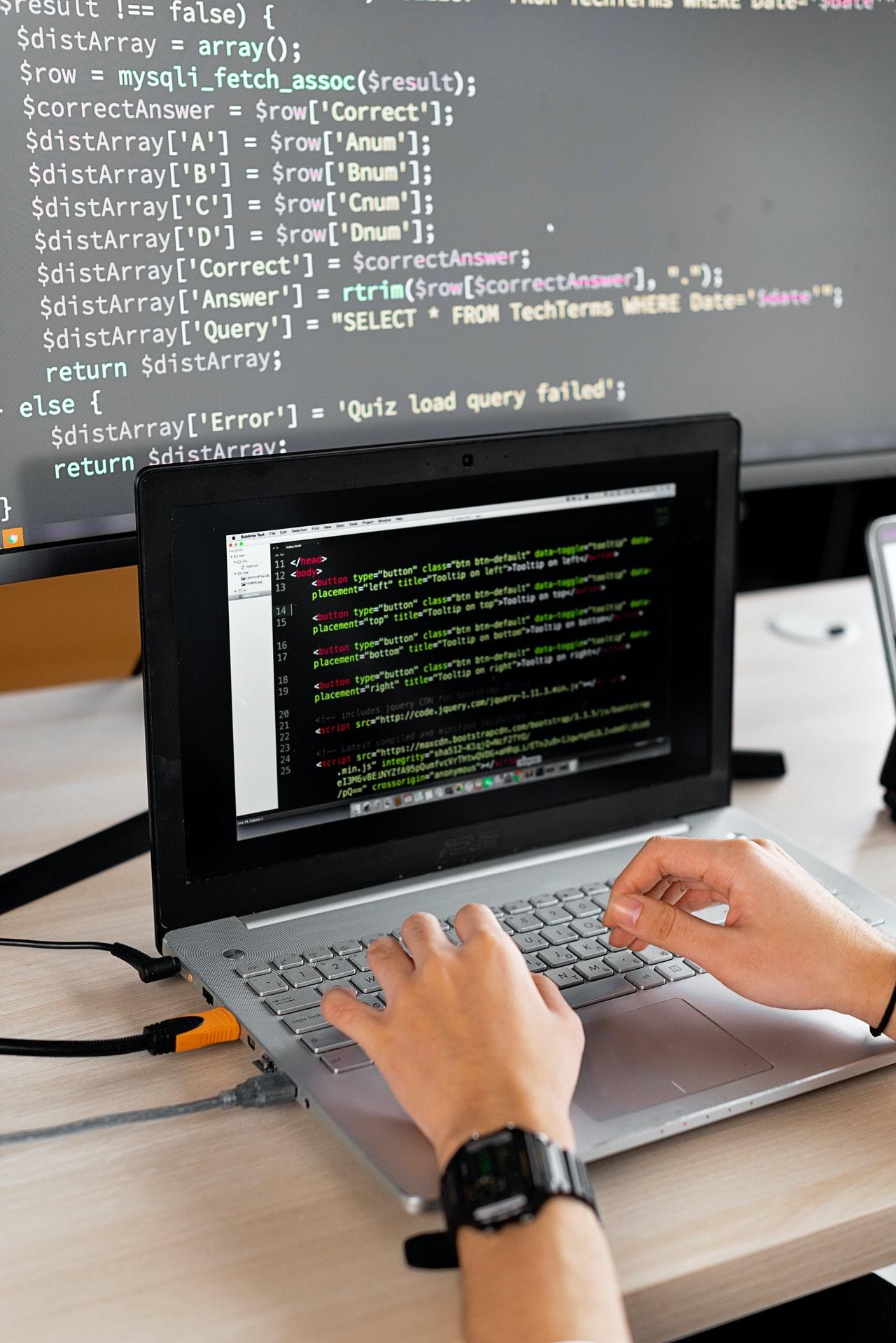 Persona programando con dos pantallas.