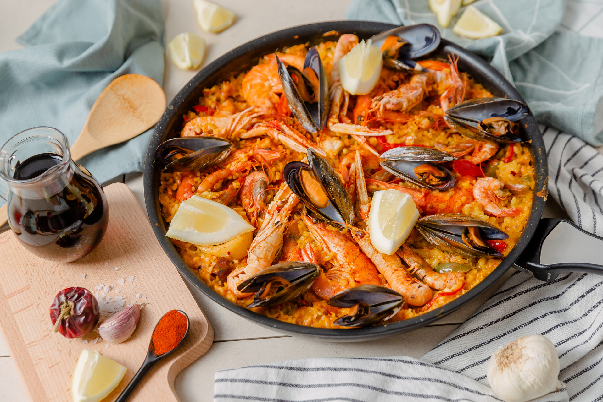 una paella servida con gambas y condimentos en los costados