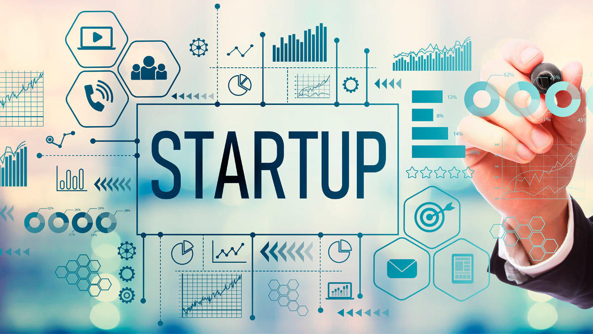 mano frente a una pantalla con iconografía de datos y gráficos alrededor de la palabra STARTUP grande
