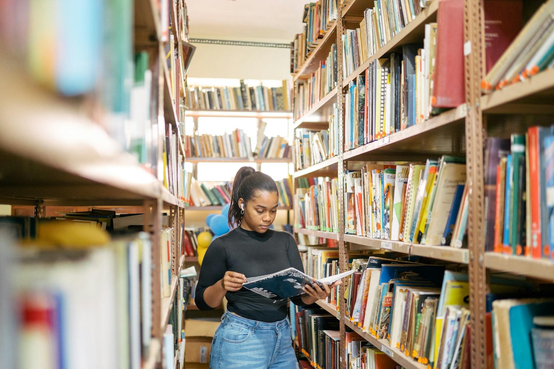 una adolescente leyendo un libro en un pasillo de biblioteca