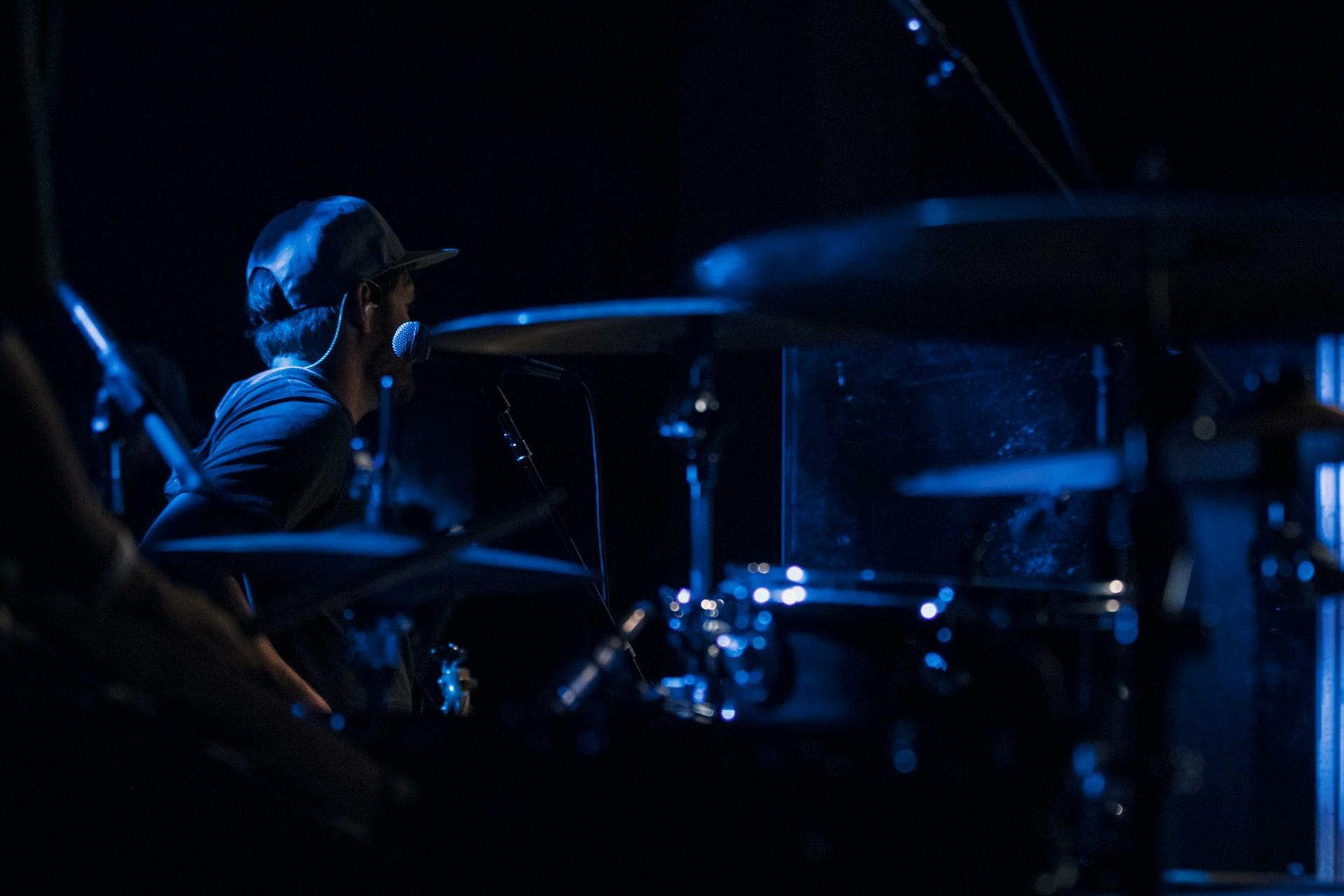 baterista tocando en escenario con colores azulados