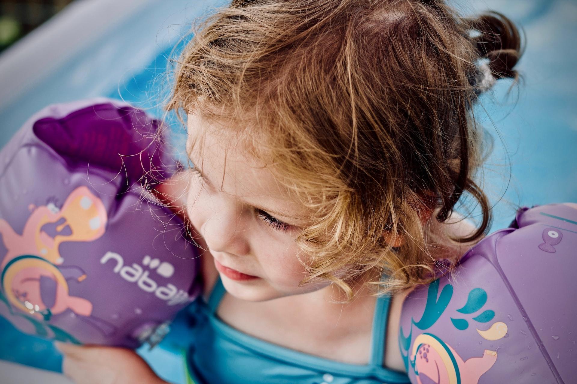 Niña en la piscina con manguitos.