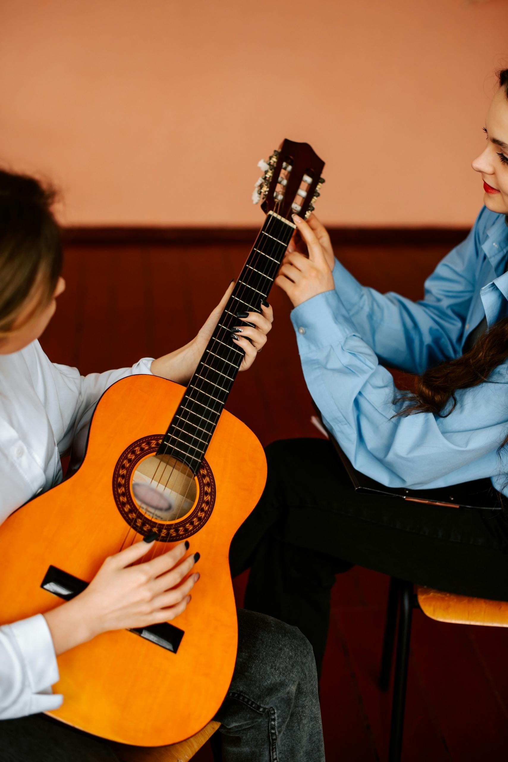 profesora enseñando guitarra a alumna