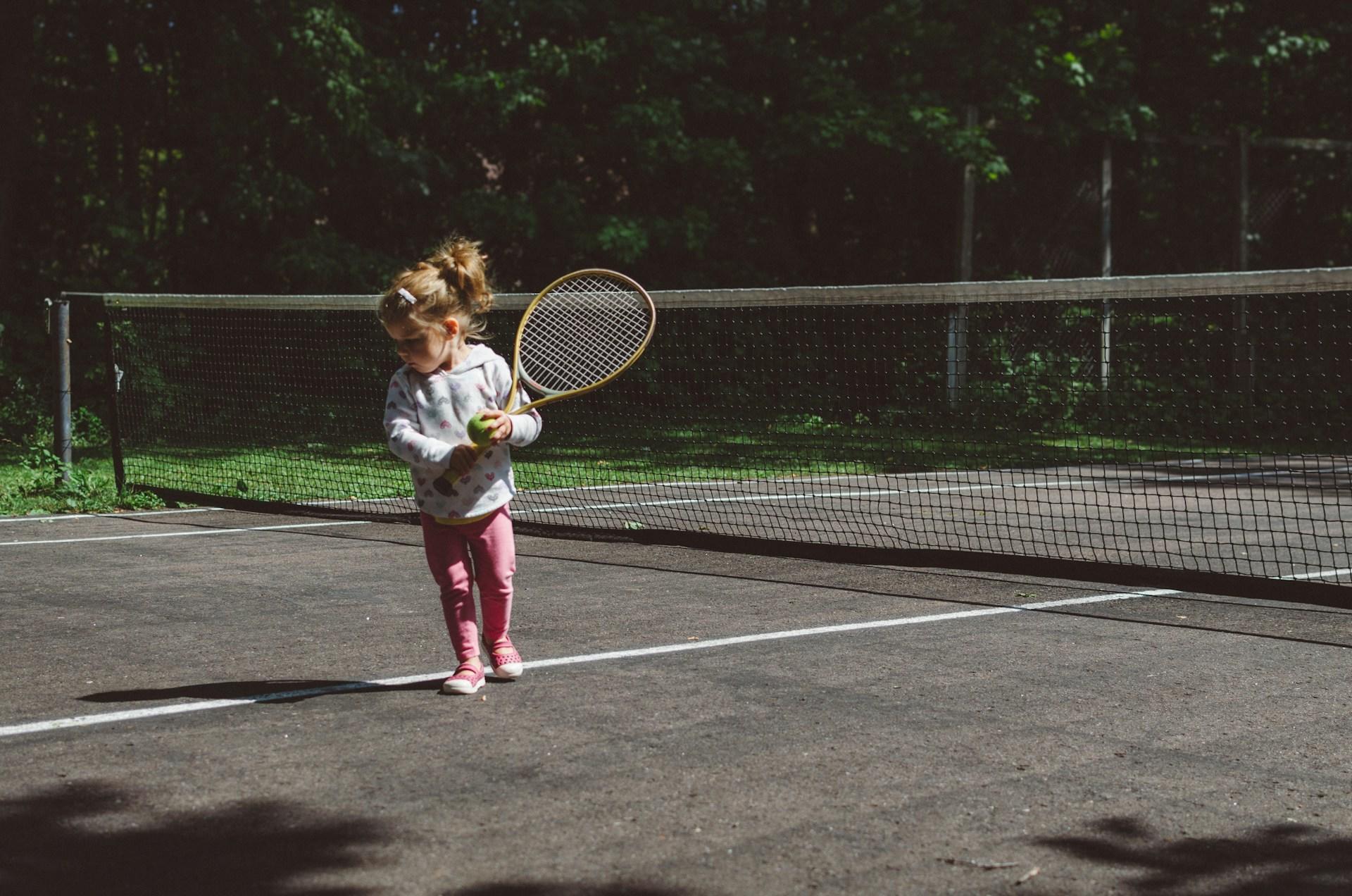 Niña pequeña jugando al tenis