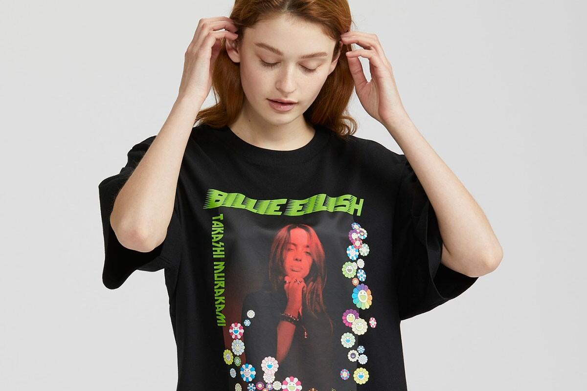 Joven con una camiseta negra con un diseño colorido que incluye un retrato en tonos rojos de Billie Eilish y detalles florales. El estilo es informal y moderno.